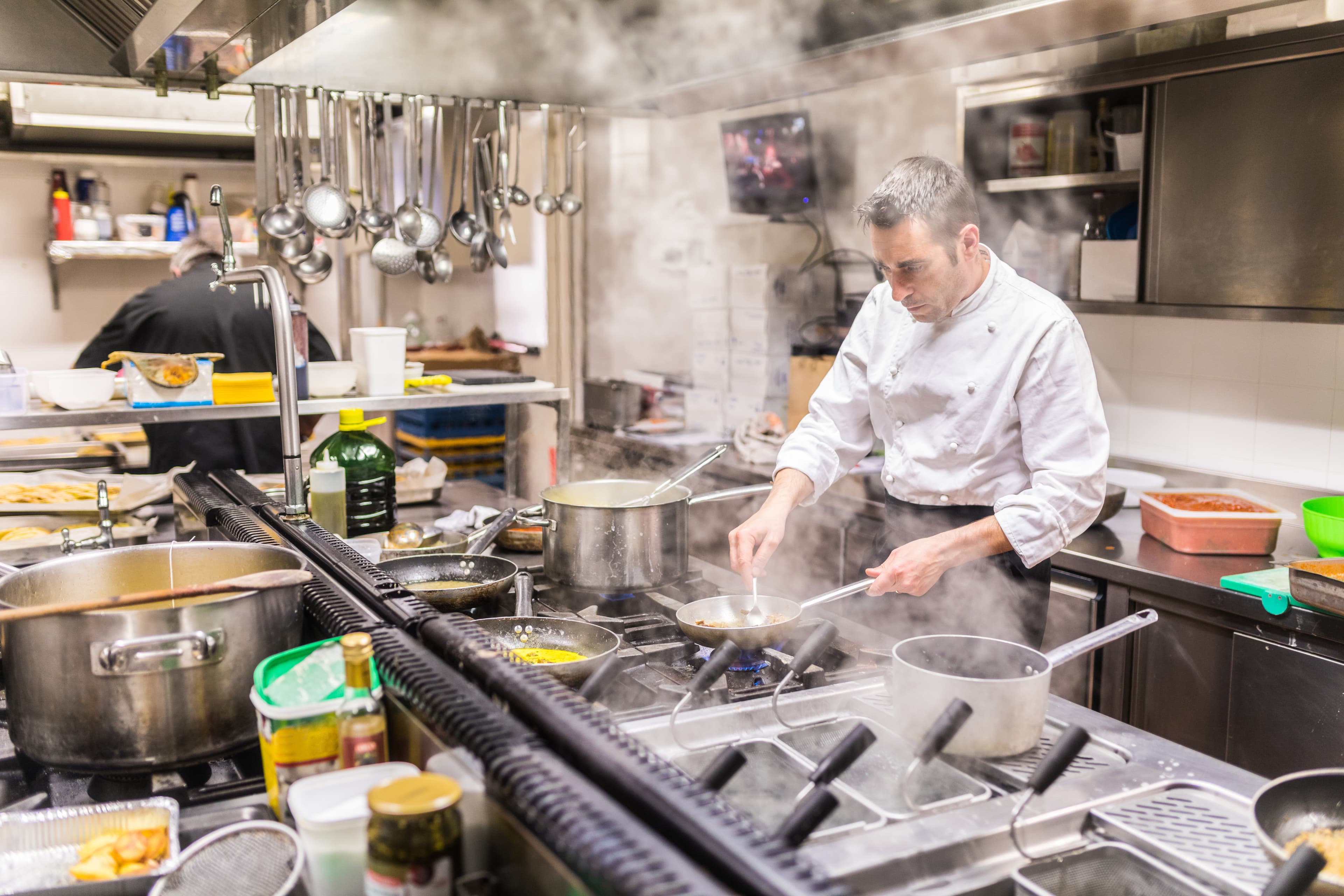 Restaurant kitchen during busy service with chef preparing food